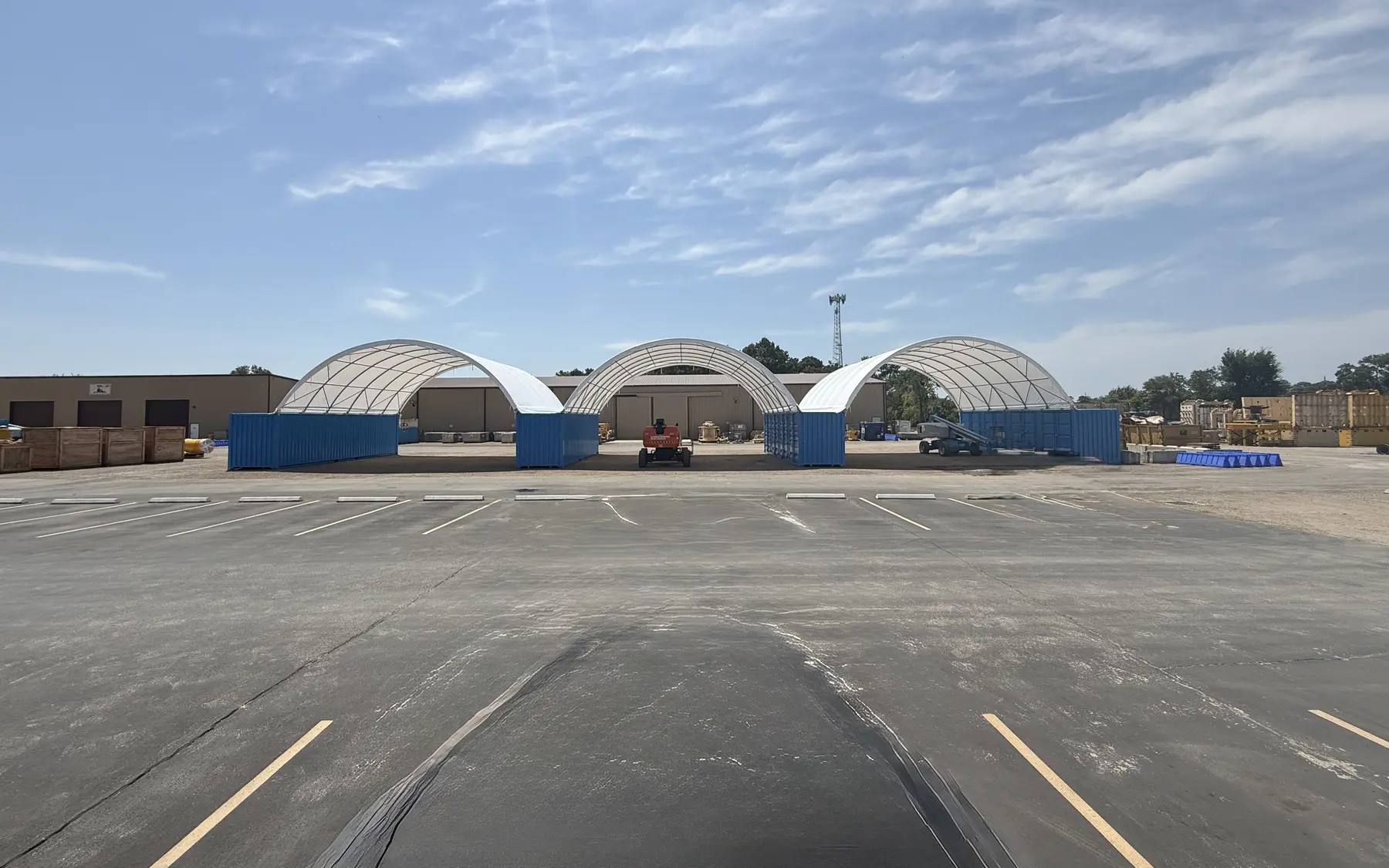 Three shipping container canopy shelters installed across an industrial equipment yard