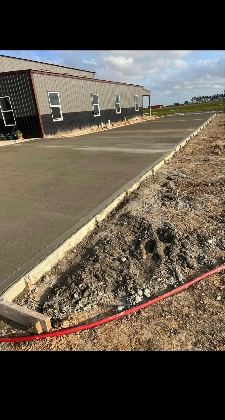 Large commercial concrete slab freshly finished beside a metal building